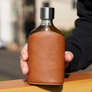 GLASS FLASK LEATHER POUCH  - Both classy and classic, this glass flask is fun to drink out of and a good conversation piece. Glass is better for drinking whiskey, liquor, or cocktails than stainless steel, and the leather pouch protects your flask.