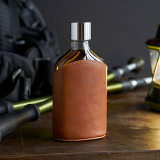 POCKET FLASK WITH LEATHER WRAP - This sleek leather flask can be slipped into any pocket or displayed on your bar cart. Authentic, genuine leather with stylish stitching brings a touch of luxury to this unique clear flask.